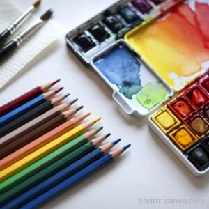 paintbrushes, colored pencils, open watercolor paint box